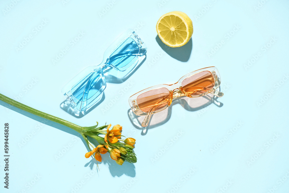 Modern sunglasses with flower on pale blue background