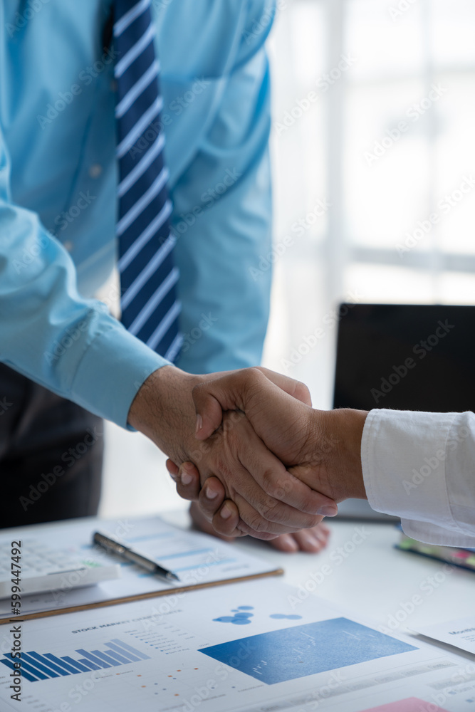 Two young Asian businessmen shaking hands and agreeing to invest in a real estate joint venture at the office. Two young Asian businessmen shaking hands and agreeing to invest in a real estate joint venture at the office.