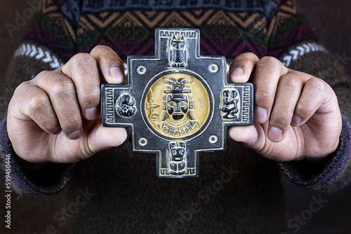 Indigenous man hold a chakana or Andean cross with the symbols of an Inca, toad, family, puma, owl. Culture and ancient history of Tiwanaku - Bolivia photo