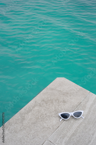 A pair of sunglasses by the swimming pool