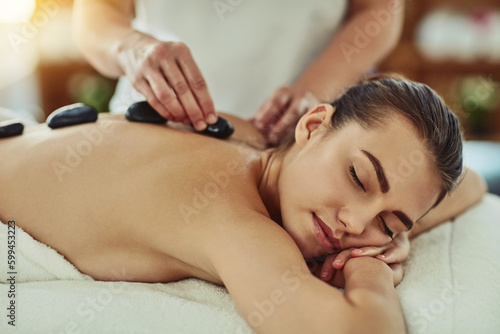 Healing with heat. an attractive young woman getting a hot stone massage at a beauty spa.