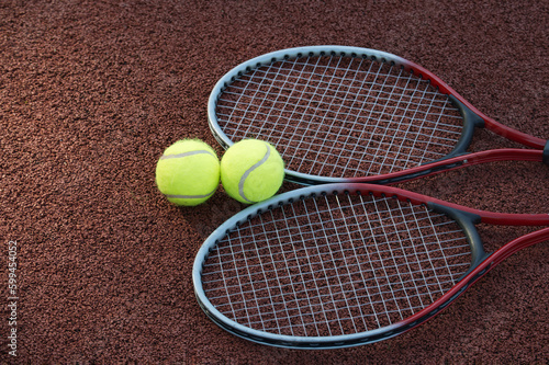 Two tennis balls and two racquets on tennis court © NetPix