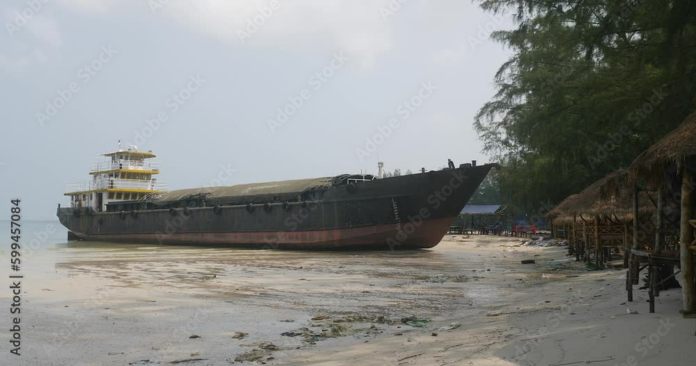 Side view of a cargo ship has beached on the sandy beach due to bad weather Side view of a cargo ship has beached on the sandy beach due to bad weather