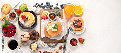 Pancakes with fresh fruits, donuts and coffee on a white background.