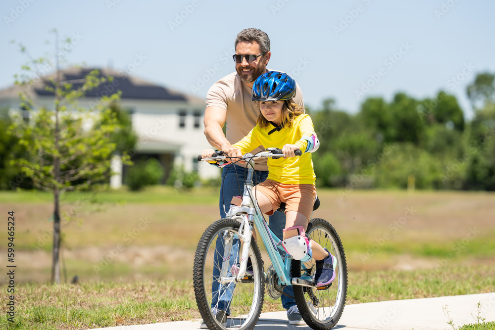 Father and son in a helmet riding bike. Little cute adorable caucasian boy in safety helmet riding bike with father. Family outdoors summer activities. Fathers day. Childhood and fatherhood.
