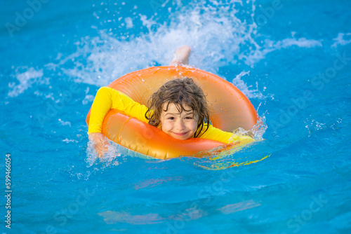 Little boy with rubber ring in swimming pool. Summertime fun. Little kid swimming in pool. Kid in swimming pool. Kid relax swim on inflatable ring. Summer vacation concept. © Volodymyr