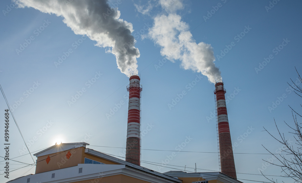 Smoke from industrial pipes against blue sky close up. Industrial zone. Environmental pollution. Smoke from industrial pipes against blue sky close up. Industrial zone. Environmental pollution.