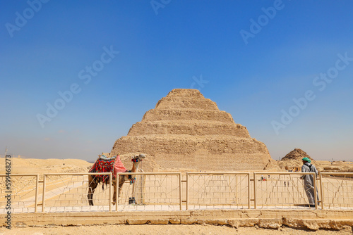 Step Pyramid of Saqqara, the oldest surviving large stone building in the world, with a camel in Giza, Egypt. Pharaoh Djoser circa 2650 BC.