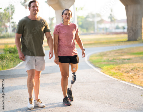 Exercise walking Asia woman with prosthetic leg and friend in the park 