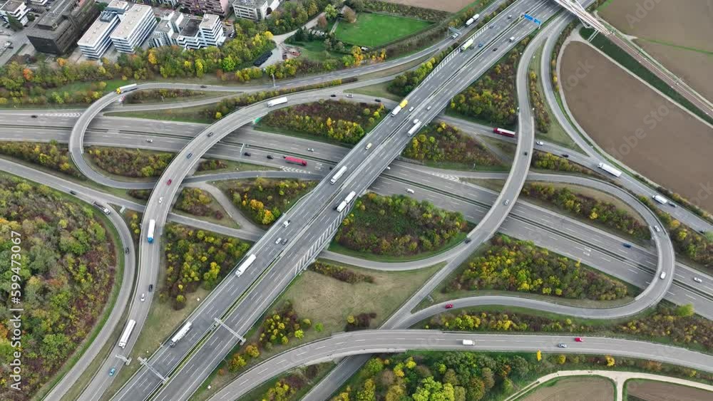 Aerial drone view of a multi-level highway intersection with moving cars near the city of Stuttgart, Germany. Trucks move along a multi-level road junction. The concept of the urban. Aerial drone view of a multi-level highway intersection with moving cars near the city of Stuttgart, Germany. Trucks move along a multi-level road junction. The concept of the urban.