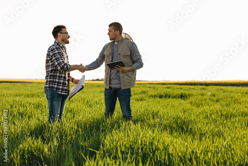 Two farmers greet each other in the field.