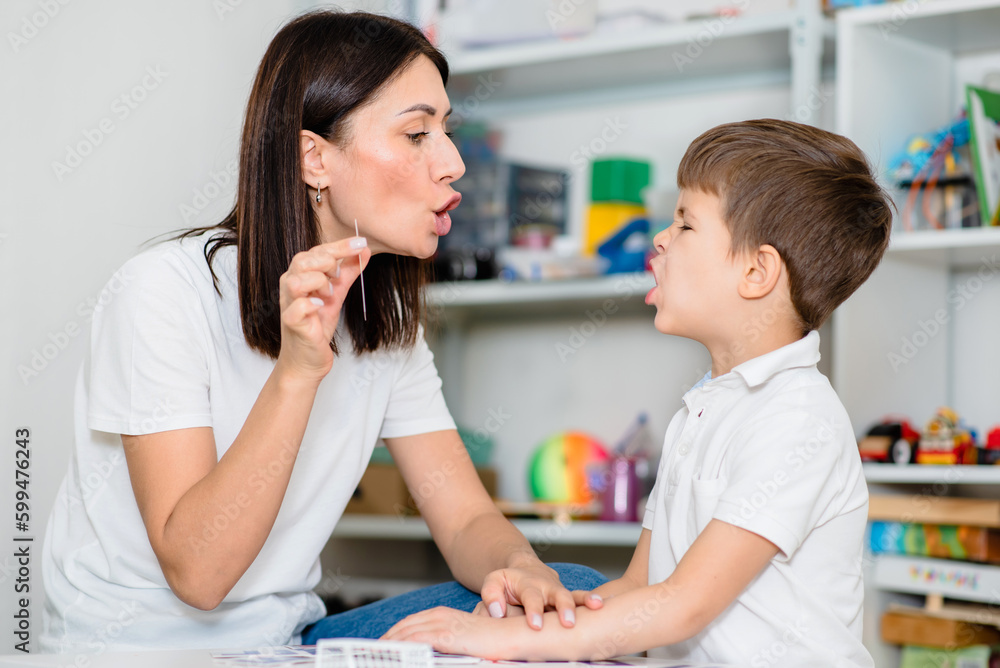 Beautiful woman speech therapist teaches boy the correct pronunciation of words and sounds in the office Beautiful woman speech therapist teaches boy the correct pronunciation of words and sounds in the office