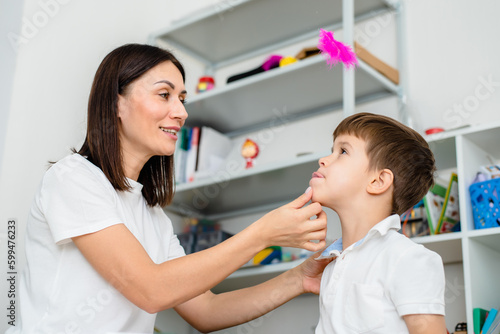 A cute boy with a speech therapist is taught to pronounce the letters, words and sounds.