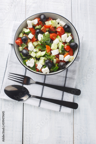 Turkish Shepherds Salad with tomato, cucumber, onion, pepper and cheese closeup on the bowl on the wooden table. Vertical top view from above photo