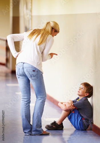 Teacher, student and scolding child at school for bad behaviour, problem or attitude. Angry woman pointing and talking to punish naughty boy for discipline, lesson or education fail in hallway photo