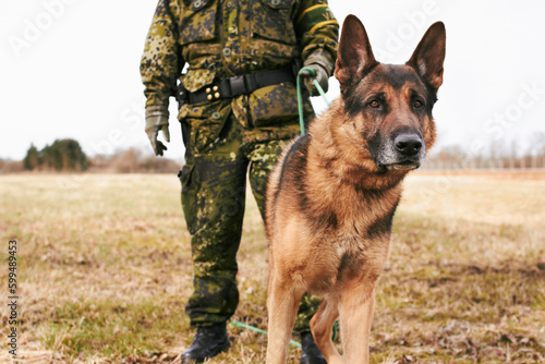 Portrait, focus and german shepherd or service dog or security in uniform and male soldier with puppy on leash outdoors. Military, courage and pet ready for army mission or tactical recruit in gear © Fannie H/peopleimages.com