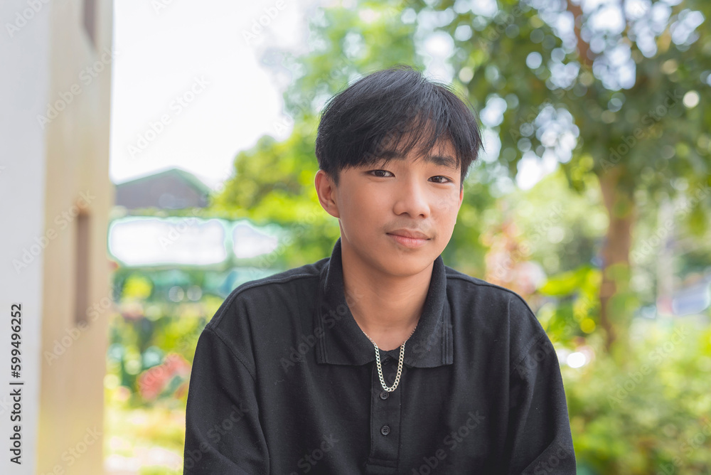 A close- up picture of a good looking young guy in a black polo shirt staring sweetly at the camera and smiling softly. Trees and plants is seen in the background. A close- up picture of a good looking young guy in a black polo shirt staring sweetly at the camera and smiling softly. Trees and plants is seen in the background.