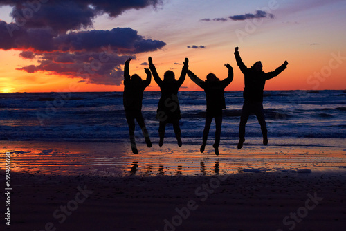 Sunset, beach and silhouette of jumping friends in nature, freedom and celebrating travel outdoor. Shadow, jump and group of people at the ocean at sunrise for adventure, celebration or sea vacation