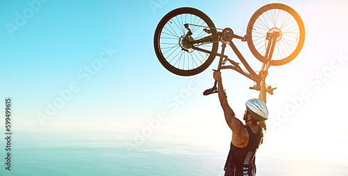 Success doesnt come to you you go to it. Rearview shot of a male cyclist lifting his mountain bike into the air.
