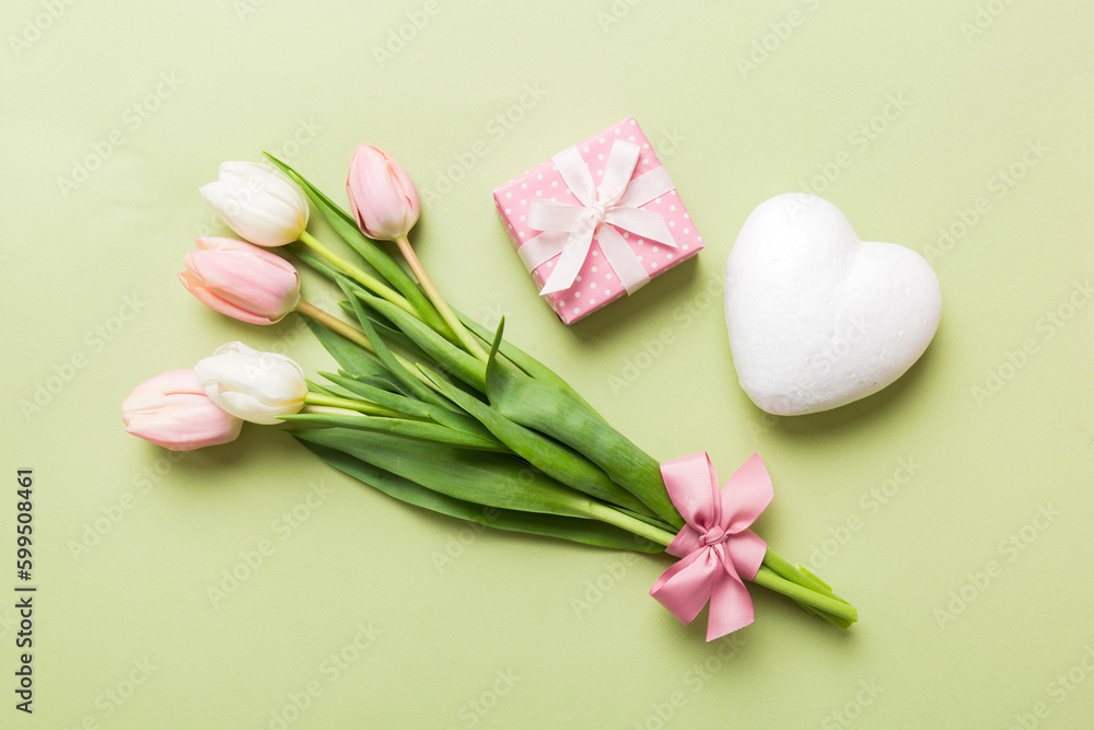 Pink tulips flowers and gift or present box on colored table background. Mothers Day, Birthday, Womens Day, celebration concept. Space for text top view Pink tulips flowers and gift or present box on colored table background. Mothers Day, Birthday, Womens Day, celebration concept. Space for text top view