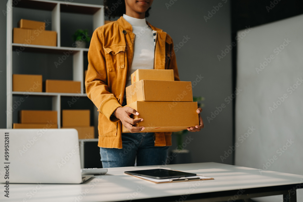  Woman hand using a laptop, smartphone and tablet and writing notebook at the office of her business online shopping. In home office.