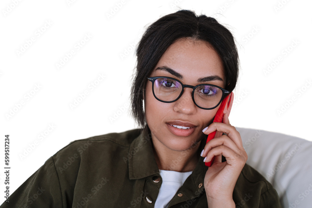 Confident Beautiful Brazilian young woman in glasses talking by phone looking at camera. Pretty African American female against transparent background received using cell phone. Business people