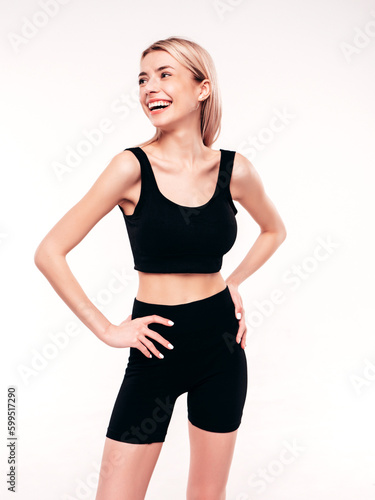 Young beautiful smiling blond female in summer black cycling shorts costume clothes. Sexy carefree woman posing on white in studio. Positive model having fun. Cheerful and happy