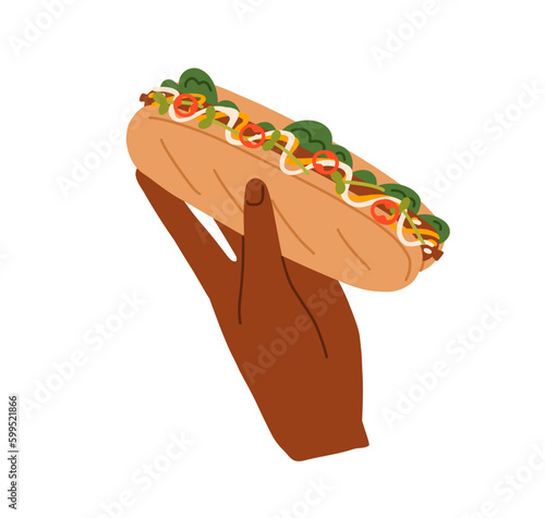 Hand holding hot-dog. American street fast food. Takeaway snack with long bun...