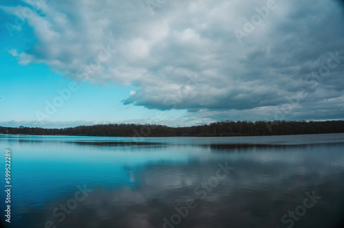 Dramatic clouds over lake with a forest. Alsace nature