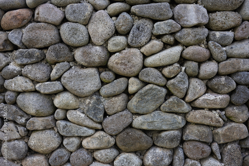 Solid texture of large gray round stones. Frontal view of a stone wall. Solid texture of large gray round stones. Frontal view of a stone wall.