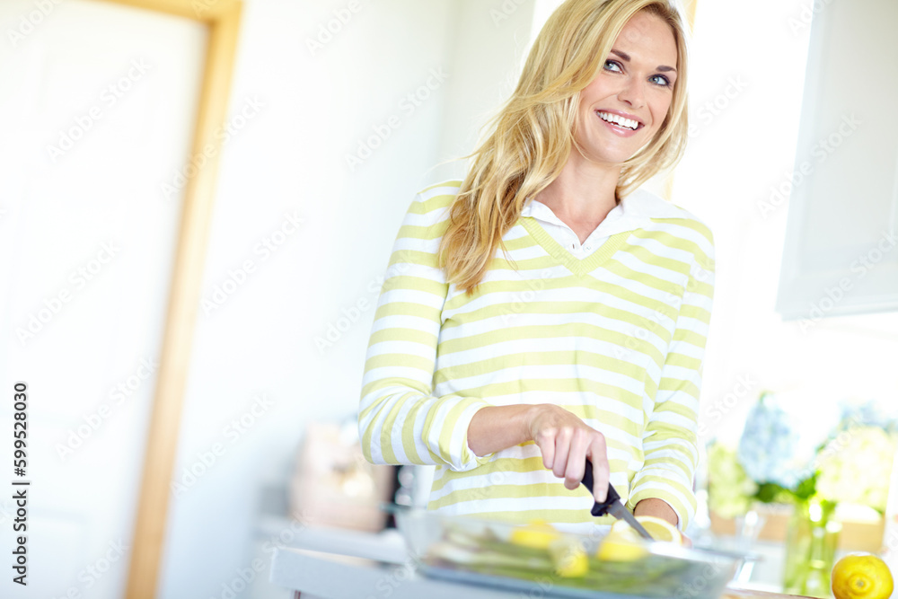 Thinking of all the uses for these lemons...Attractive young blonde woman slicing lemons in her kitchen at home.