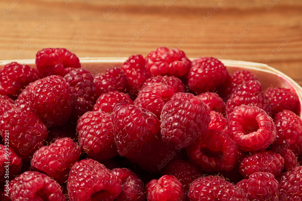 delicious fresh raw red raspberries in natural eco-friendly packaging in a basket of peeled hardwood veneer on a wooden table closeup. harvest. healthy food. diet. summer. vitamins delicious fresh raw red raspberries in natural eco-friendly packaging in a basket of peeled hardwood veneer on a wooden table closeup. harvest. healthy food. diet. summer. vitamins