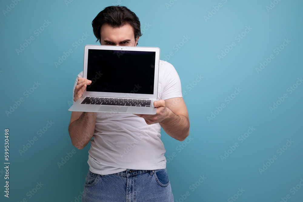 bearded brunette man in white tank top with laptop on studio background with copyspace bearded brunette man in white tank top with laptop on studio background with copyspace