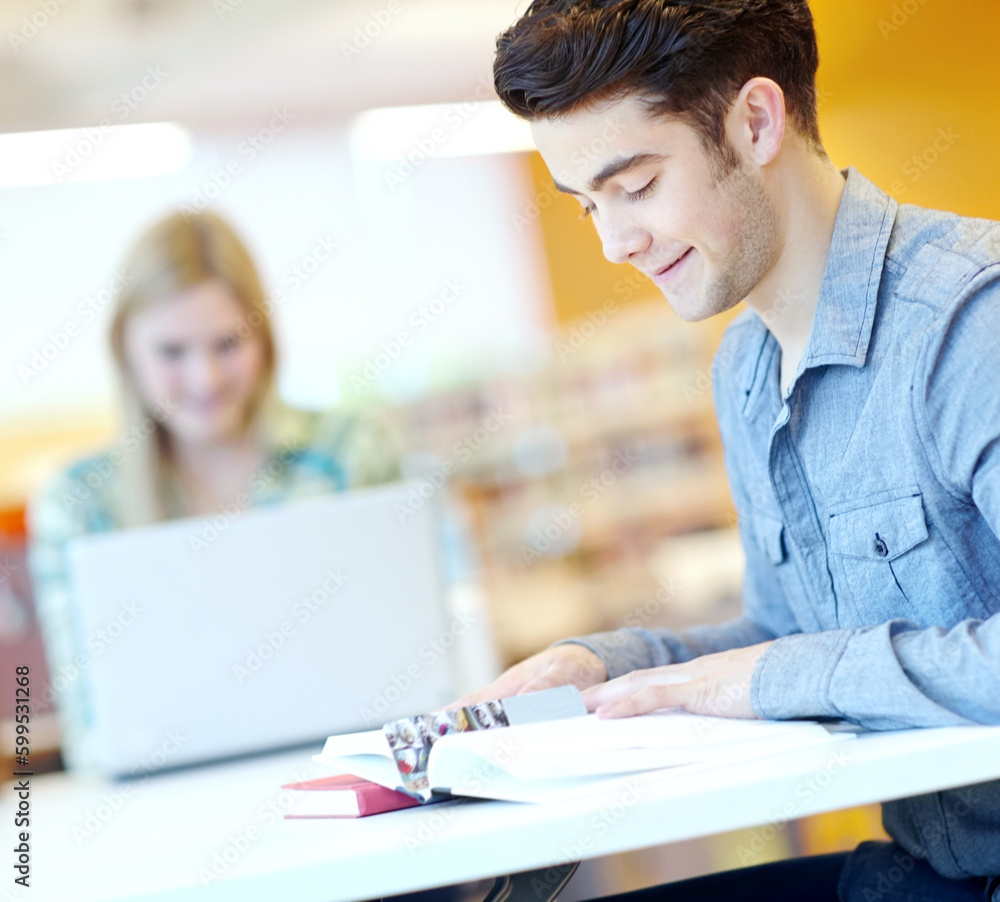 Hitting the books. Attractive male student with his study buddy in the background. Hitting the books. Attractive male student with his study buddy in the background.