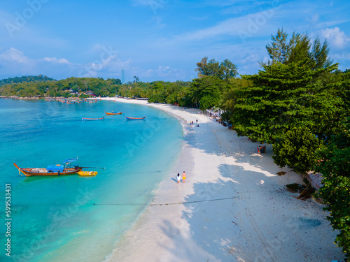 A couple of men and women walking on the beach of the tropical Island Koh Lipe Southern Thailand