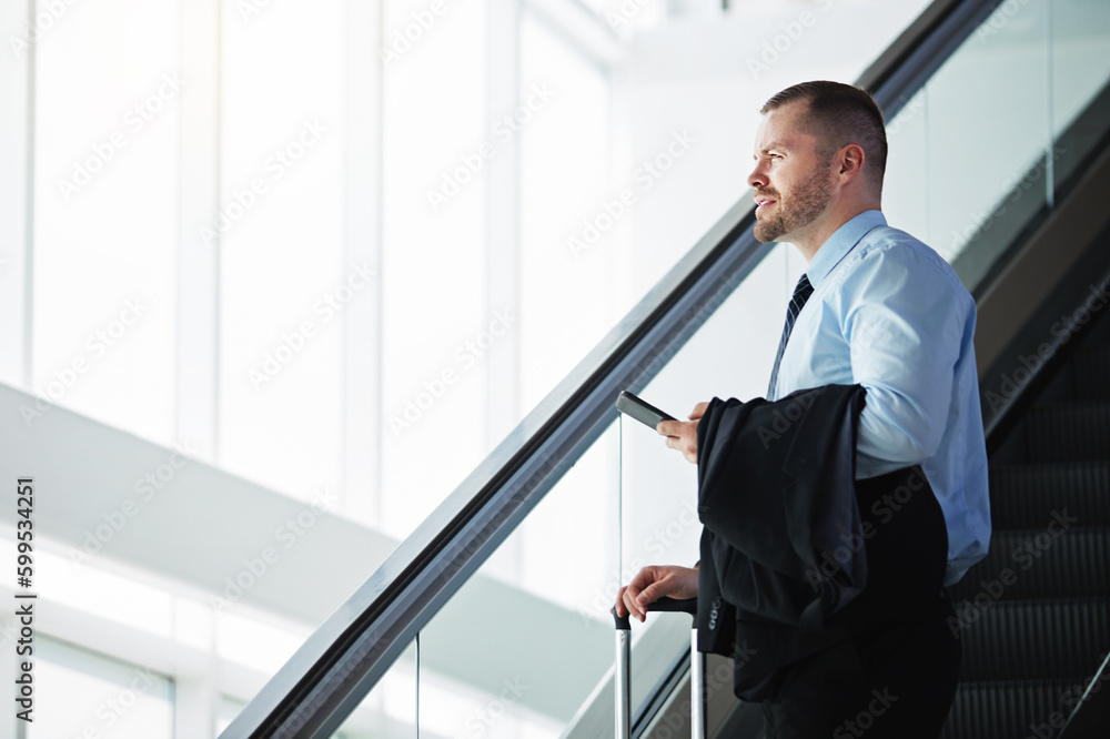 Taking his business global. a businessman traveling down an escalator in an airport. Taking his business global. a businessman traveling down an escalator in an airport.