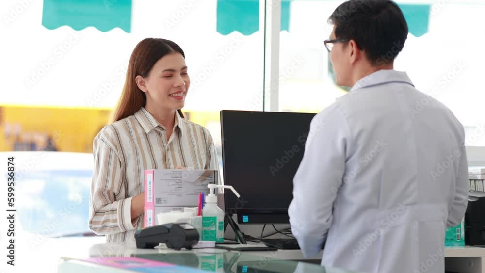 Asian man Pharmacists provide consultation and explain the use of medication to patients who purchase medication at the pharmacy. Shelves with drug and Health Care product Asian man Pharmacists provide consultation and explain the use of medication to patients who purchase medication at the pharmacy. Shelves with drug and Health Care product