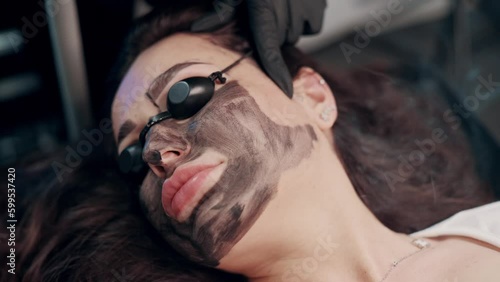Facial cleansing procedure with laser carbon peeling in a spa salon. Close up top view.