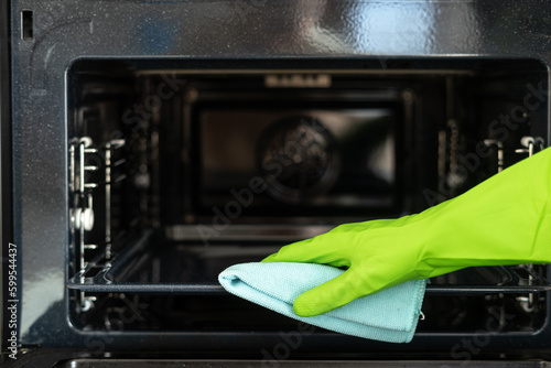 Housekeeper cleaning electric microwave using detergent and rag