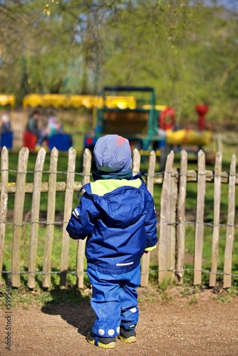 Child behind a fence watches a train