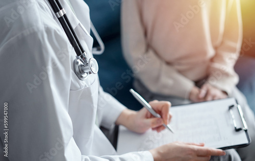 Doctor woman and kid boy patient at home medical exam. The pediatrician filling up medical form on clipboard, close up. Medicine, healthcare concepts