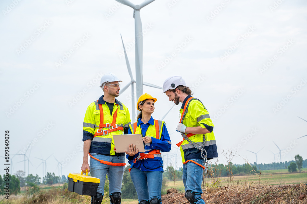 Group of engineers are working with a blueprint in wind turbine farm,Wind power station,Renewable and clean energy concept. Group of engineers are working with a blueprint in wind turbine farm,Wind power station,Renewable and clean energy concept.