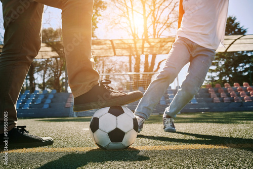 Father and Son play football on stadium outdoors, Happy family bonding, fun, players in soccer in dynamic action playing in sunny day, holidays time.  © Andrii IURLOV