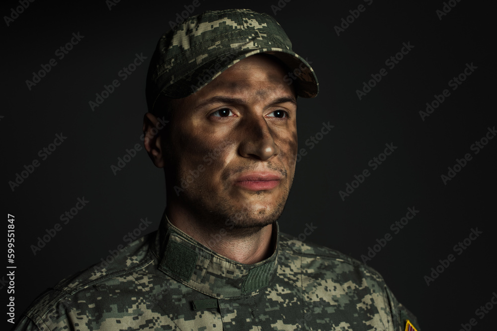 soldier with dirt on face standing in uniform and cap suffering from ptsd isolated on grey.