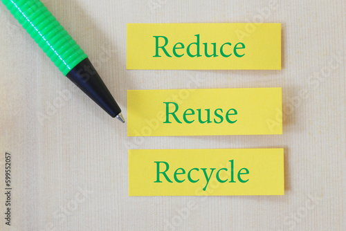 Green Pen pointing Text on yellow paper note with the words of Reduce, Reuse and Recycle. photo