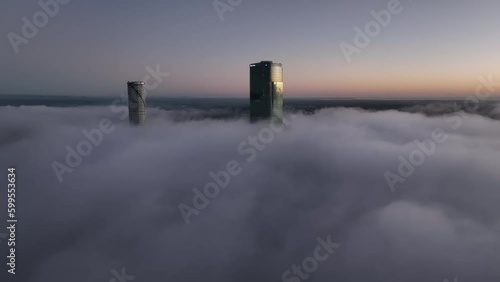 Aerial shot above a cloudy foggy Brisbane City, with only the tops of sky scrapers being visible. The One Skyscraper and The Meriton Sky Scraper in shot. photo