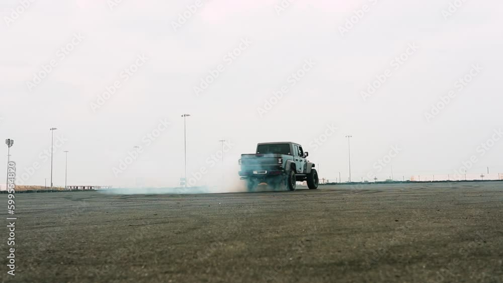 Slow motion shot of a large SUV doing donuts on a race arena creating a cloud of smoke Slow motion shot of a large SUV doing donuts on a race arena creating a cloud of smoke