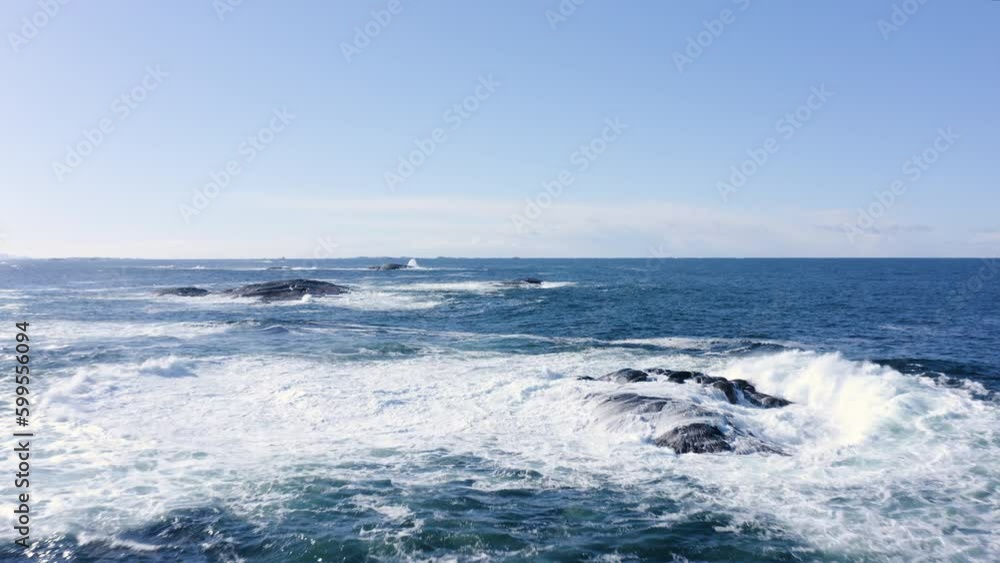 Aerial shot of rough waters. A wave splashes into a reef as the drone is flying by. Aerial shot of rough waters. A wave splashes into a reef as the drone is flying by.