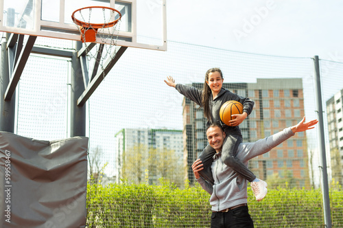 Happy father and teen daughter outside at basketball court. photo