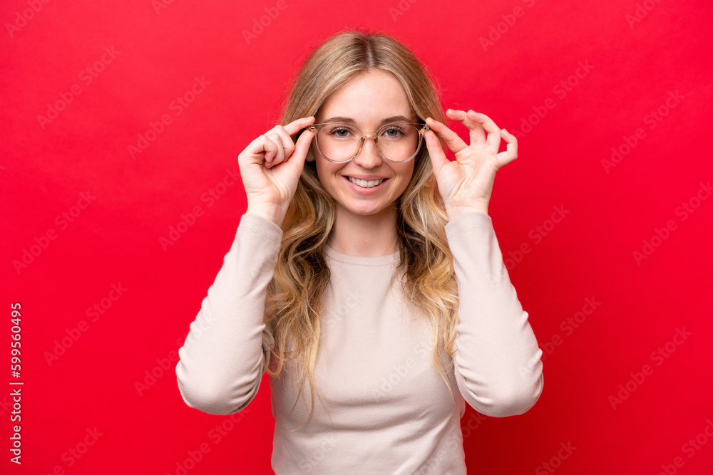 Young English woman isolated on red background With glasses with happy expression Young English woman isolated on red background With glasses with happy expression